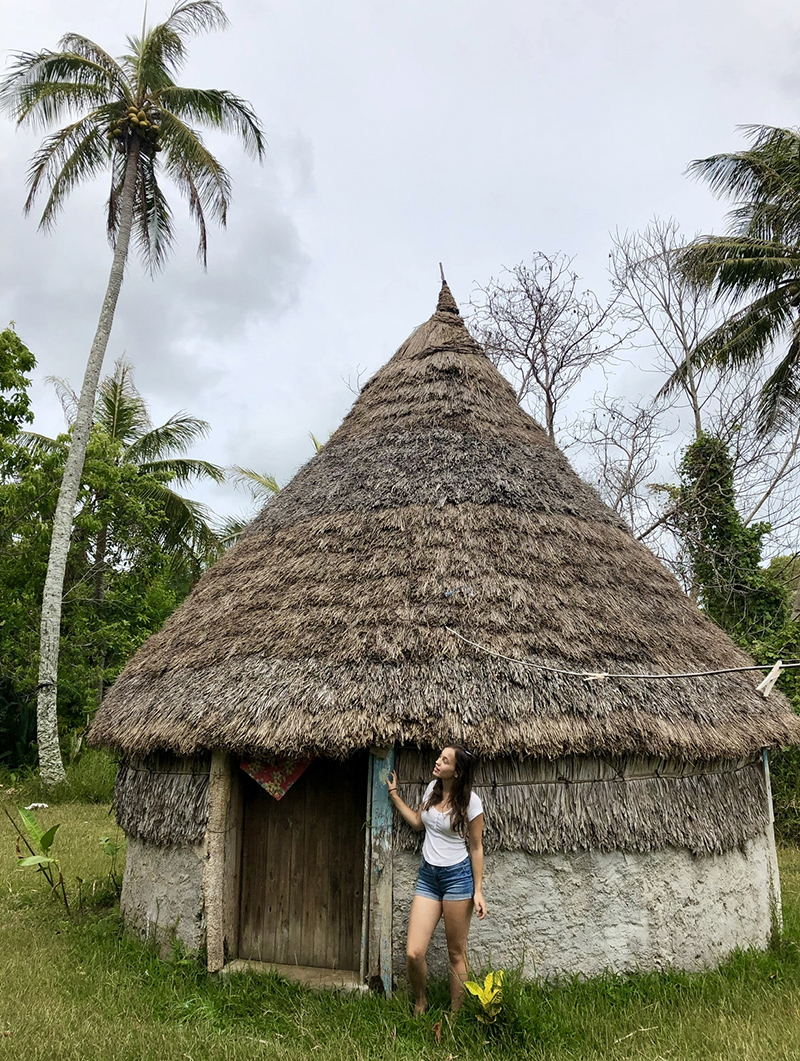 Girl standing next to a hut in New Caledonia