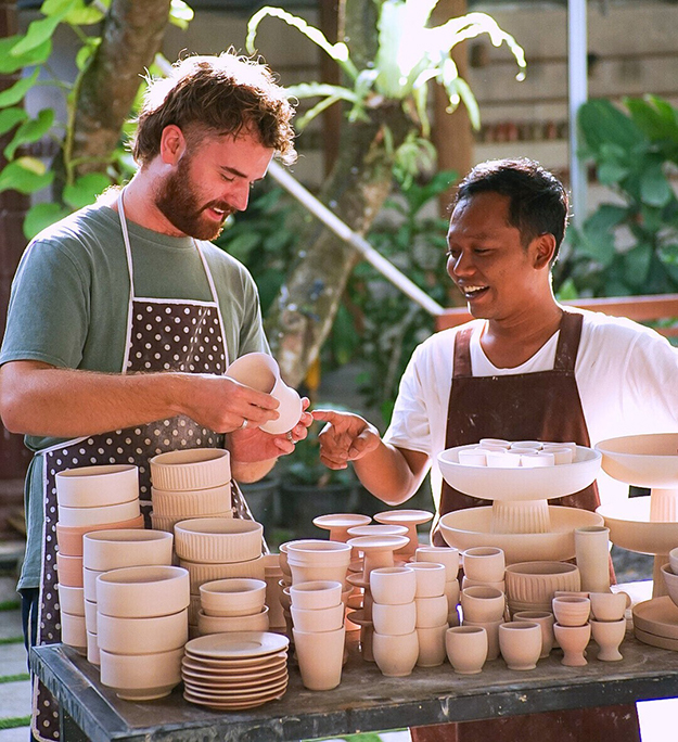 Two people standing behind a pottery display