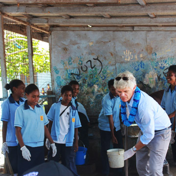 His Excellency Mr Ian Kemish holding a pole as students look on