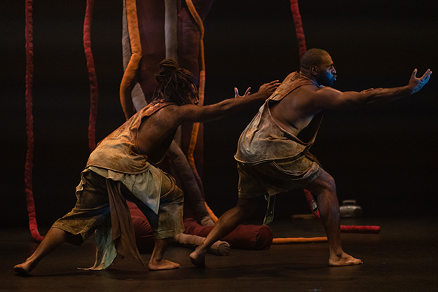 Two First Nations male dancers perform on a stage.