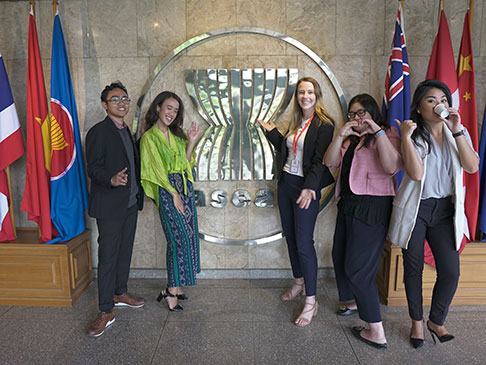 Hayley and delagrates in front of a large ASEAN logo and country flags.