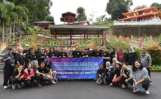 Group of people in front of a decorative building holding a banner.