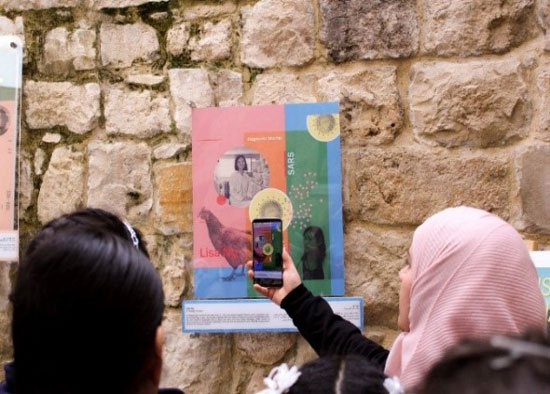 Photo of woman using her phone to access the digital version of the artwork.