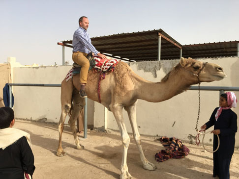 Photo of a man riding a camel.