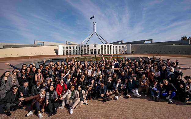 A large group of students posing together in front of Parliament House, Canberra