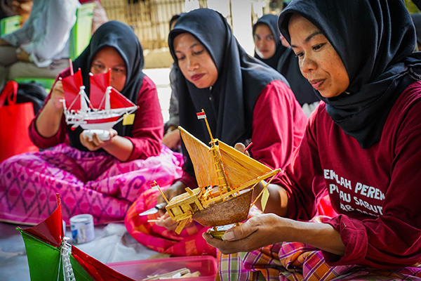 Three women working on making souvenir boat models