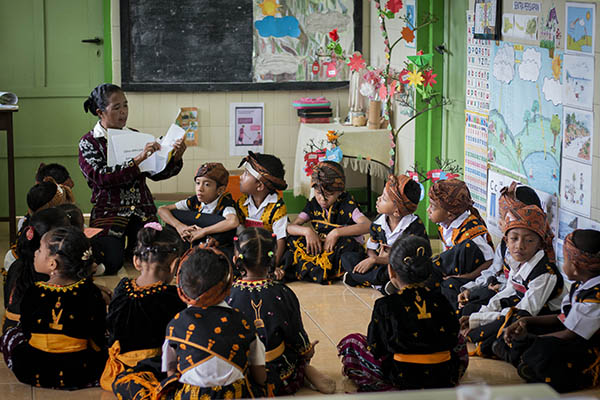 Teacher sitting on the floor surrounded by children