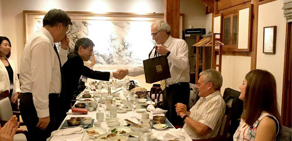 Shaking hands and exchanging gifts over a dining table