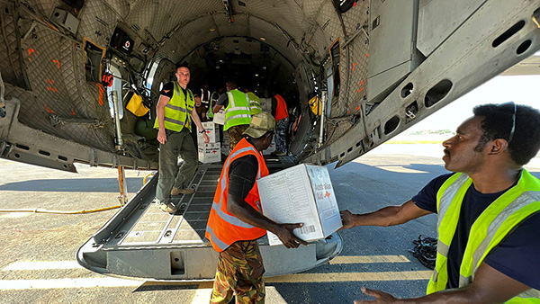 4 man unloading supplies from the back of a military aircraft