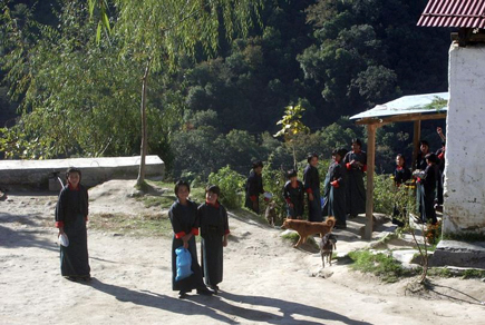 Children in long robes standing outside a building, which is sited on a steep hillside