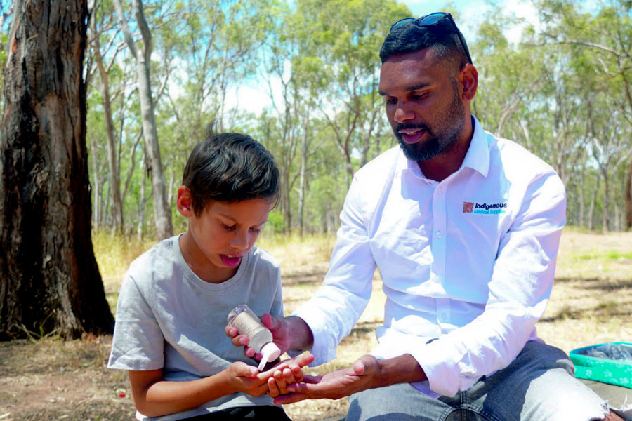 Photo of Dutjahn Custodian giving the Western Australia, Dutjahn Sandalwood Oil to a little boy.