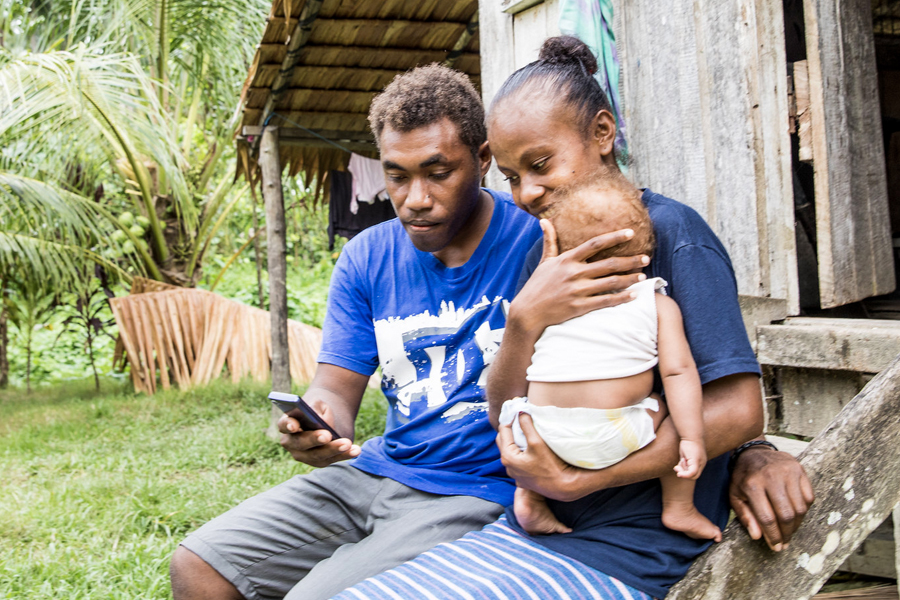 A Solomon Islands family checking their bank balance online using a mobile phone