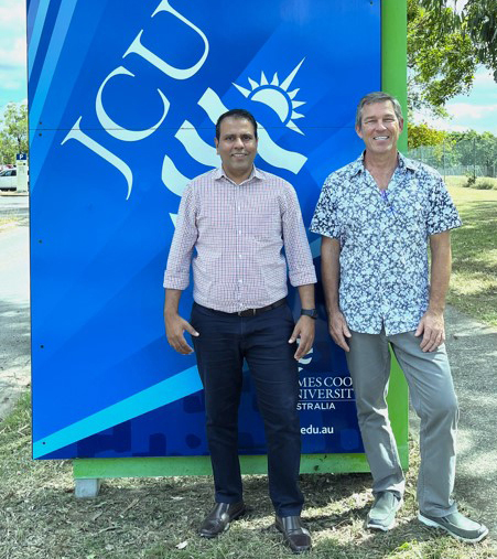 Two men standing in front of a sign