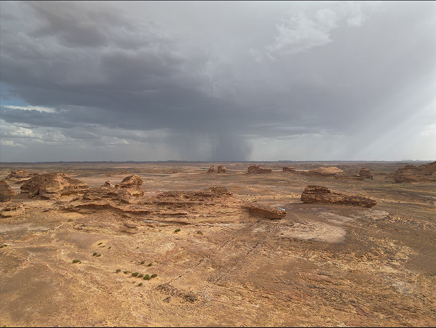 A desert landscape with a storm off in the far distance