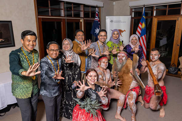 Visitors from malaysia and Australian First Nations performers pose together with hands outstretched