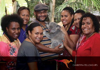 Seven women and one man from Papua New Guinea patting a koala.