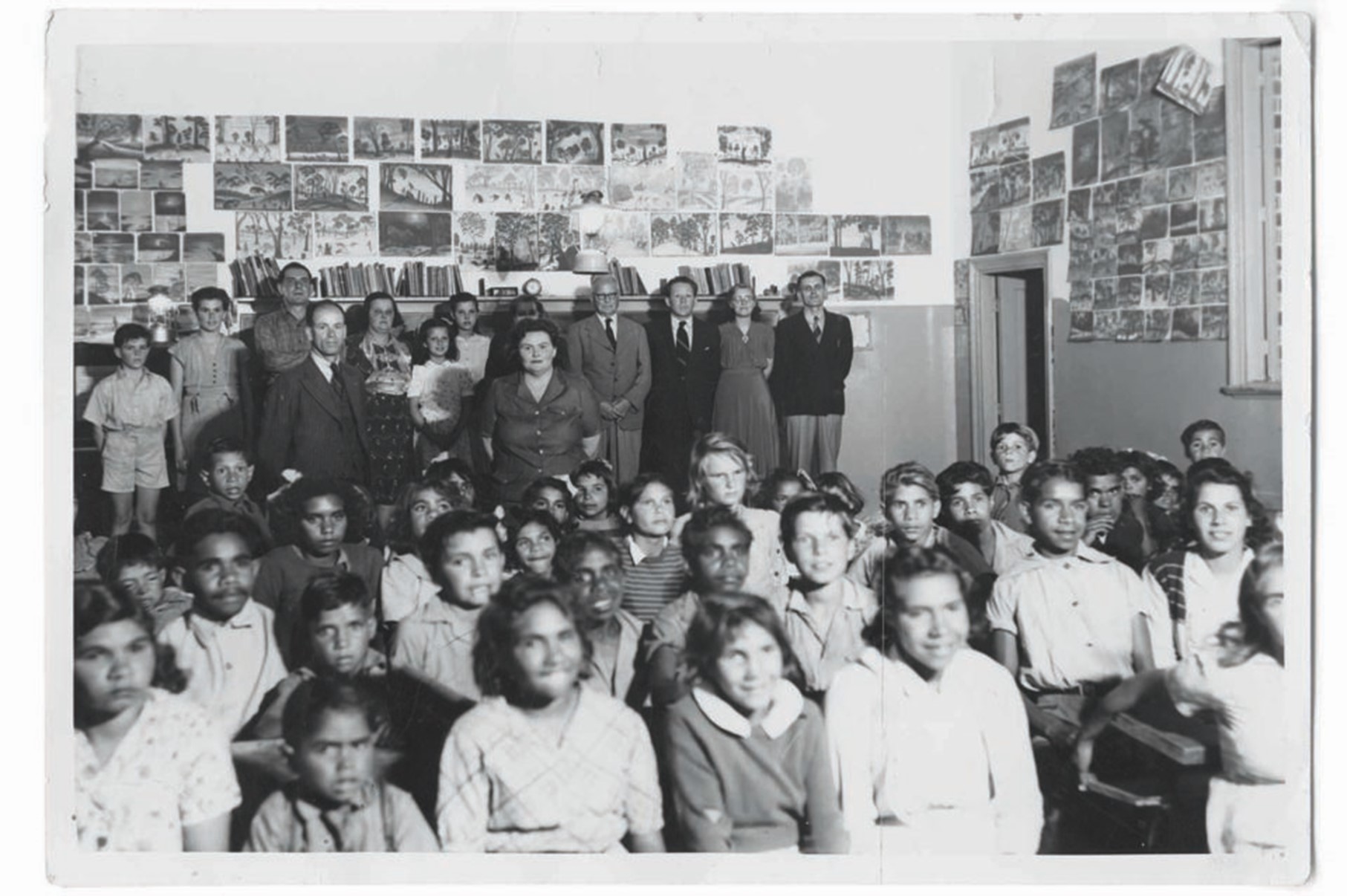 Kids seated in the classroom and adults standing at the back