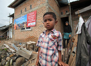 A boy stands on the front steps of a house under construction.