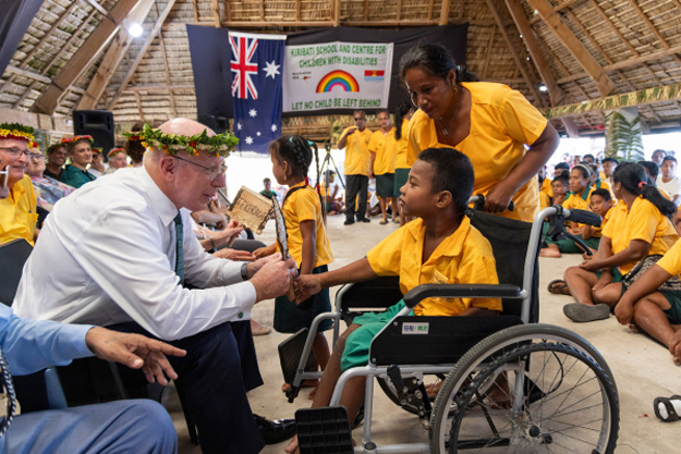 David Hurley, seated, accepts a gift from a boy in a wheelchair. 