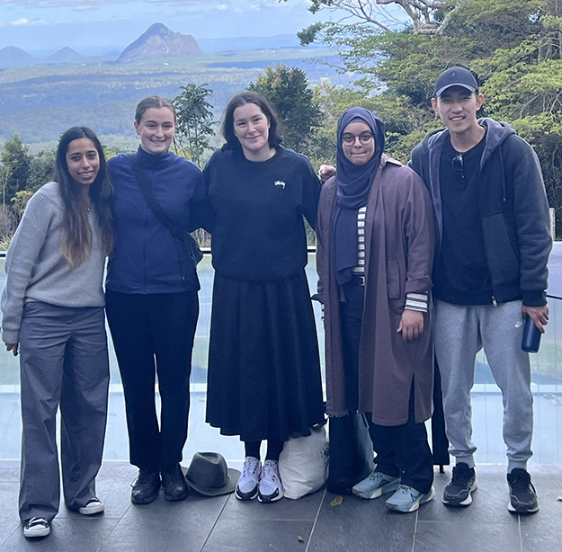 Five New Colombo Plan scholars smiling with trees and a mountain in the background