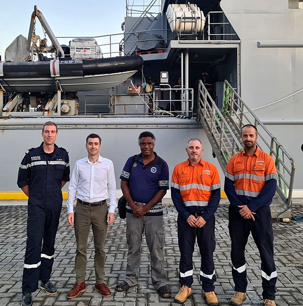 5 men standing in front of a ship.