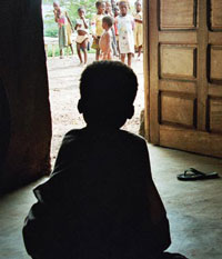 Photo of child sitting alone inside while others play outside