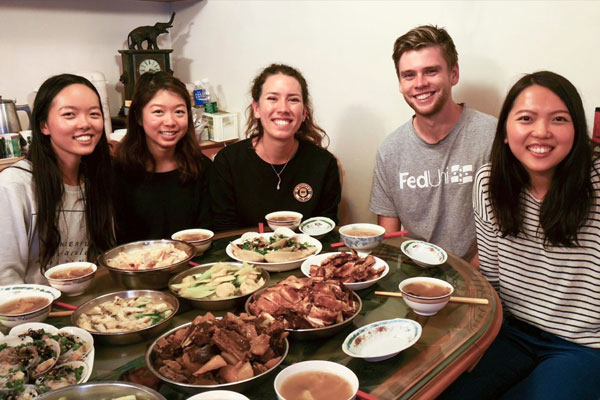 Group photo of people gathered around a dining table, ready to eat.