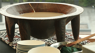 A bowl of kava sitting on a table with a bowls and a ladle around the bowl.