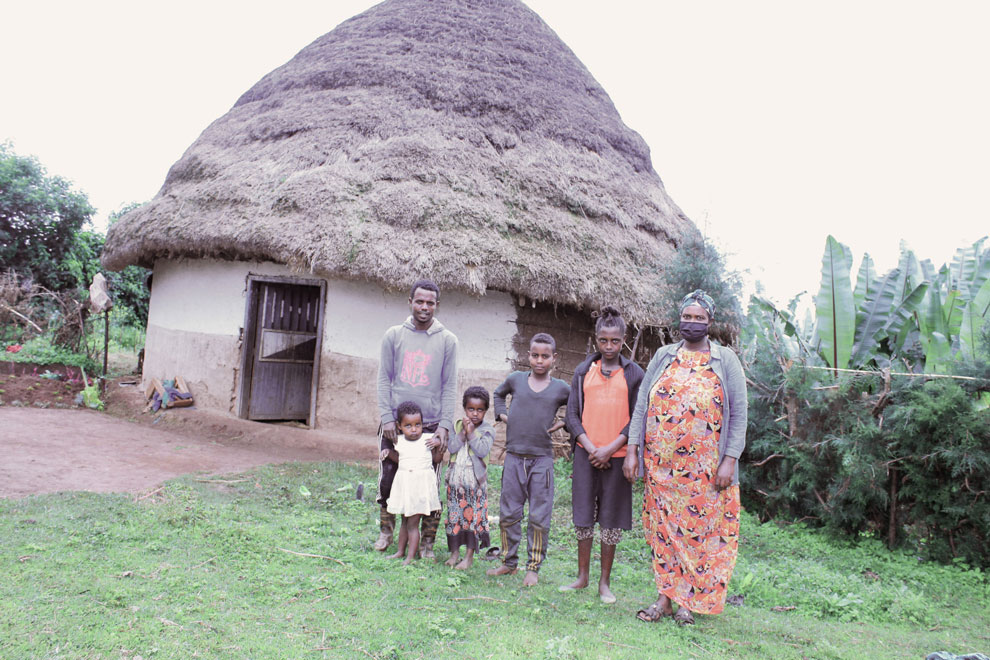 Photo of Ethiopian farmer and their family in front of their housing hut.