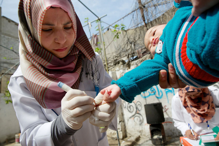 Fatima taking a blood test from a baby's finger.