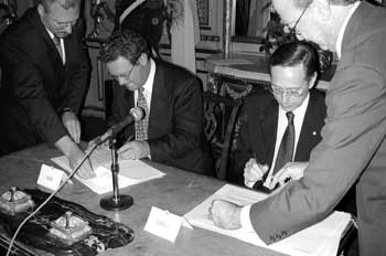 Photo of Mr Downer and Mr Giavirini signing the nuclear cooperation agreement with advisors assisting.