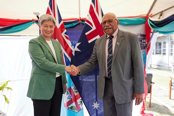 Foreign Minister Wong and Fiji Prime Minister Rabuka standing in front of their respective flags.