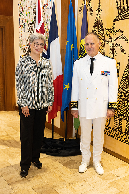 Senator Penny Wong standing in front of flags with High Commissioner of French Republic in New Caledonia Mr Louis Le Franc