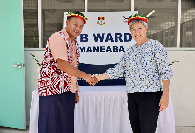 Foreign Minister Penny Wong and Kiribati Health and Medical Services Minister Dr Tinte Itinteang shake hands, wearing traditional head ware.