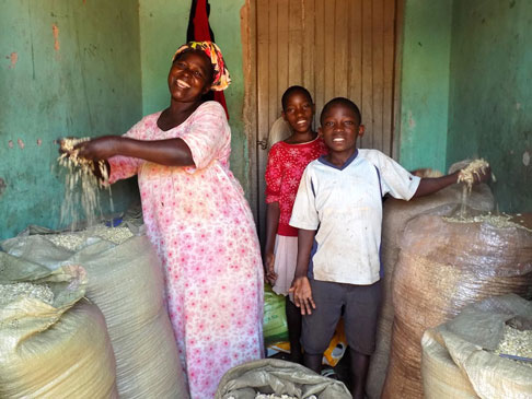 Rosemary and two boys showing bags full of maize.