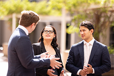 Two men and a woman standing outside talking