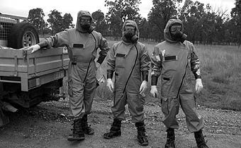 Photo of 3 inspectors in protective suits and gas masks.