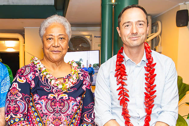 A woman and a man smiling and sitting next to each other.