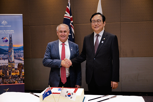 Two men standing behind a desk, shaking hands