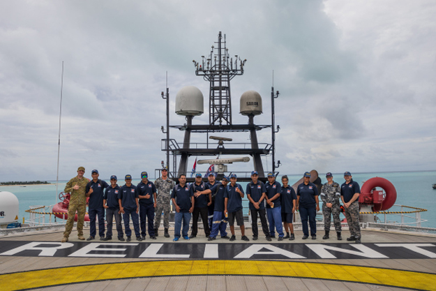 Australian defence personnel and Kiribati police standing together on the deck of the reliant