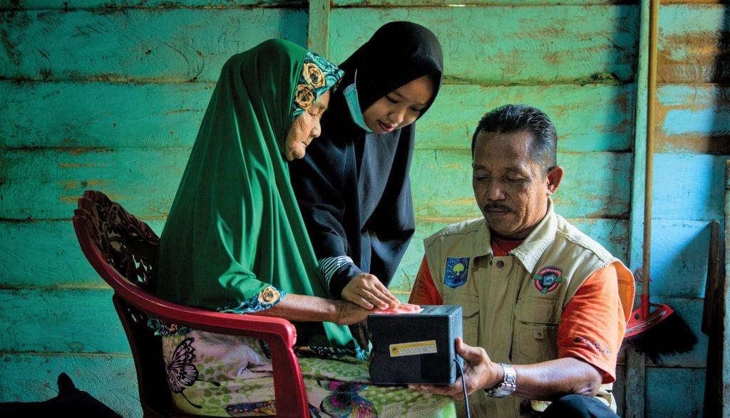 Village registration officers in South Sulawesi, Indonesia collecting information from a villager [KOMPAK/Yusuf Ahmad]