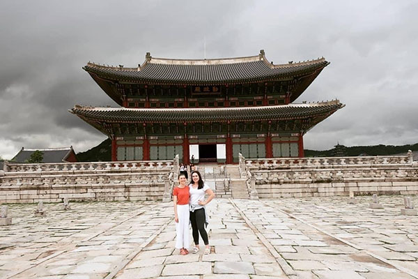 Two people standing out the front of Korean temple.