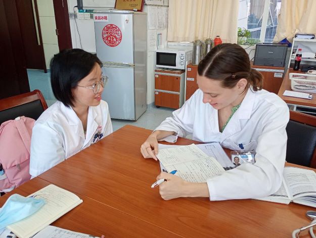 Two women seated at a desk, one woman taking notes while another speaks.