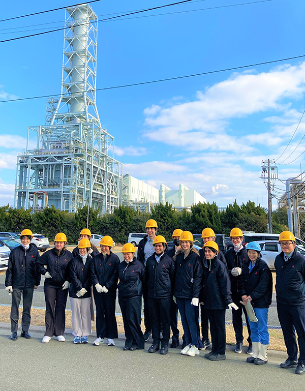 A group of people wearing yellow helmets and white gloves standing in front of a transition tower