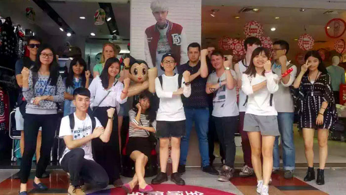 Students standing outside a store doing hand gestures