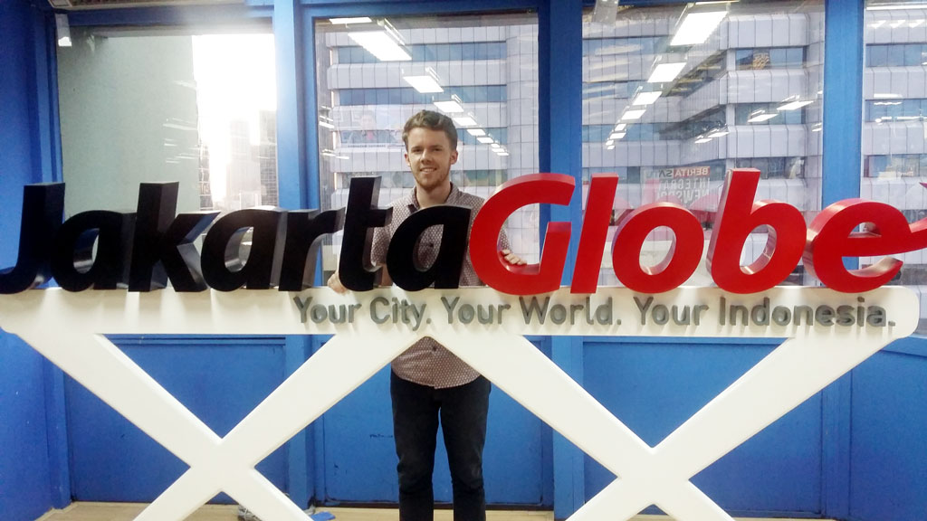 Lachlan Haycock standing behind a Jakarta Globe sign.