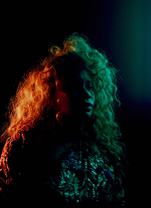 Portrait of a woman on stage, with red and green stage lighting