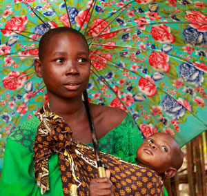 Photo of Fatima, a Tanzanian woman, holding her child and an umbrella.