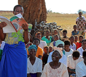 Photo of an African woman reading to her village.