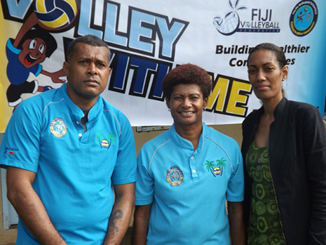 A man and two ladies photgraphed in front of a Volleyball banner